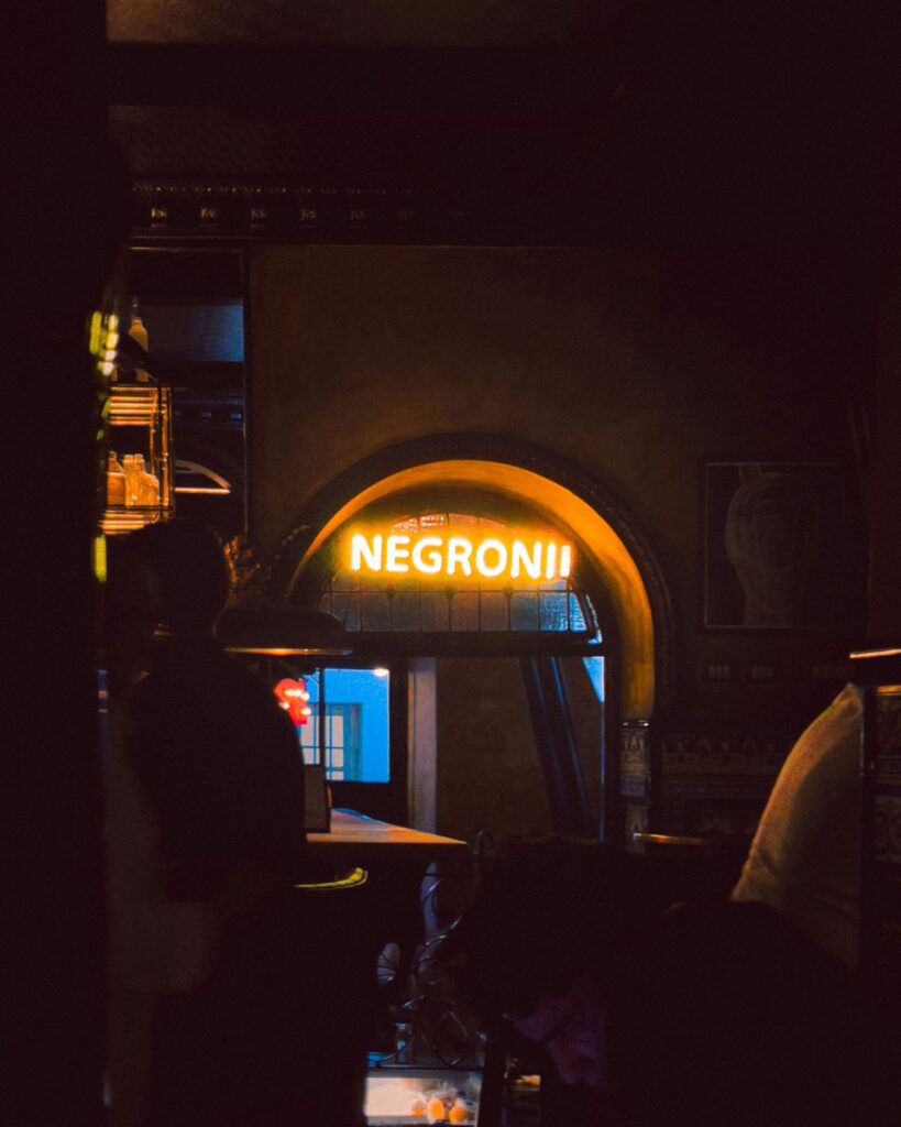 Stimmungsvolle Bar im Herzen von Brera, Mailand: ein warm leuchtendes Neonschild mit der Aufschrift ‚Negroni‘ lockt Genießer in eine der angesagtesten Aperitivo-Adressen der Stadt.