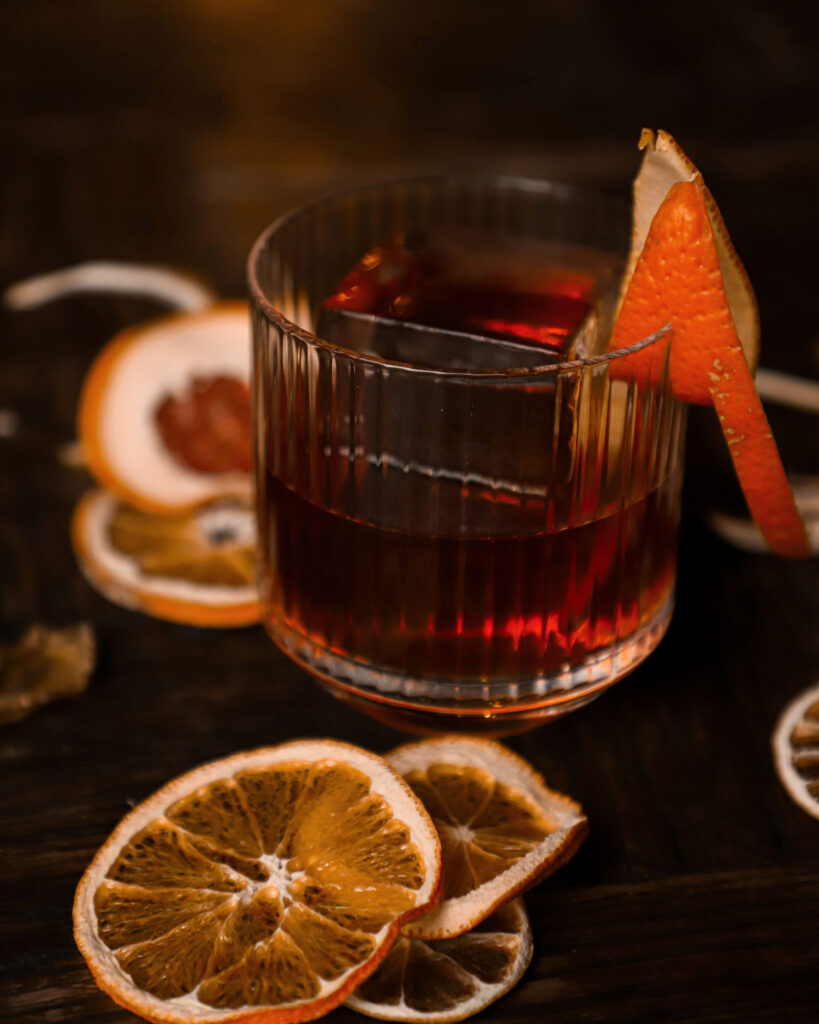 Perfekt gemixter Negroni in einem Kristallglas, garniert mit Orangenzeste, umgeben von getrockneten Orangenscheiben – die Essenz des Mailänder Aperitivo-Lifestyles in Brera.
