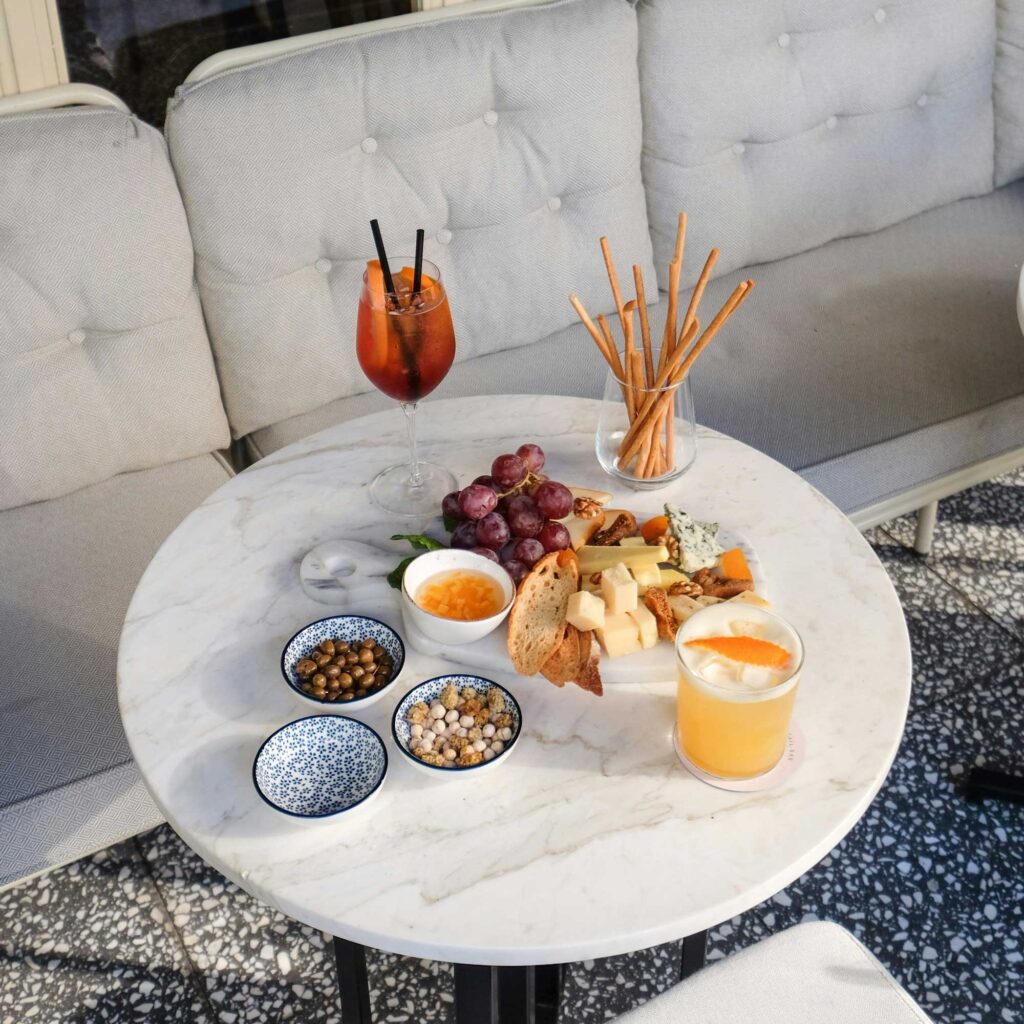 Centro Italia summer aperitivo scene featuring a refreshing drink with ice and orange slice, olives, snacks, and citrus fruits, offering tips for the best Italian aperitivo experience.