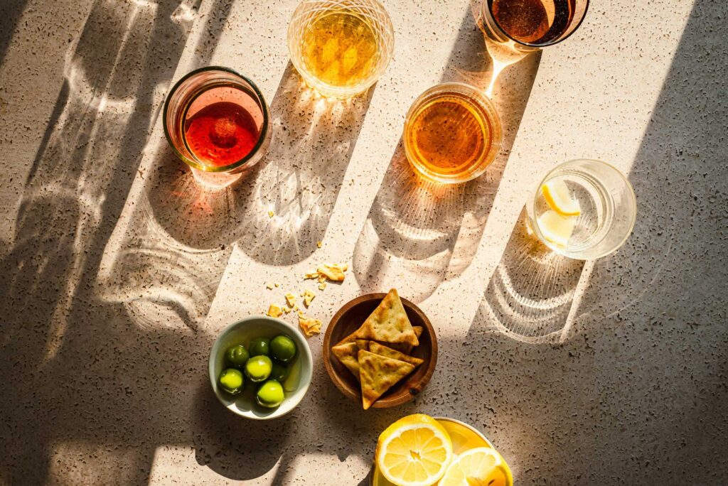 Centro Italia summer aperitivo scene featuring a refreshing drink with ice and orange slice, olives, snacks, and citrus fruits, offering tips for the best Italian aperitivo experience.