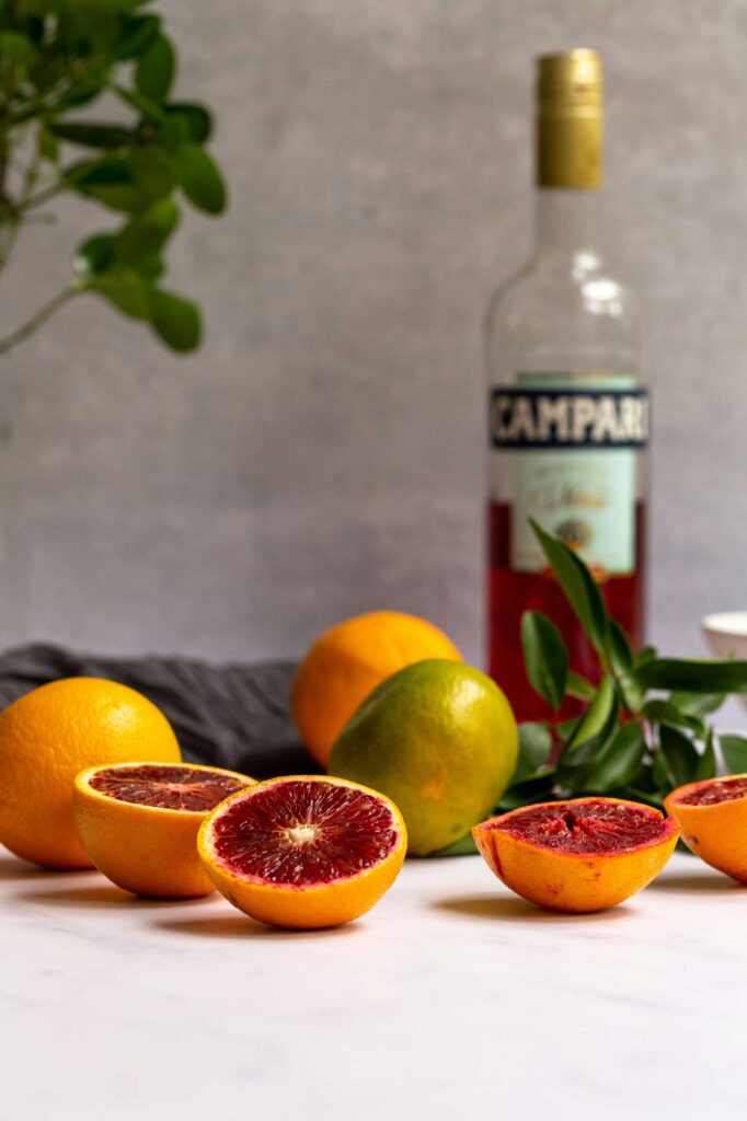 Centro Italia summer aperitivo scene featuring a refreshing drink with ice and orange slice, olives, snacks, and citrus fruits, offering tips for the best Italian aperitivo experience.