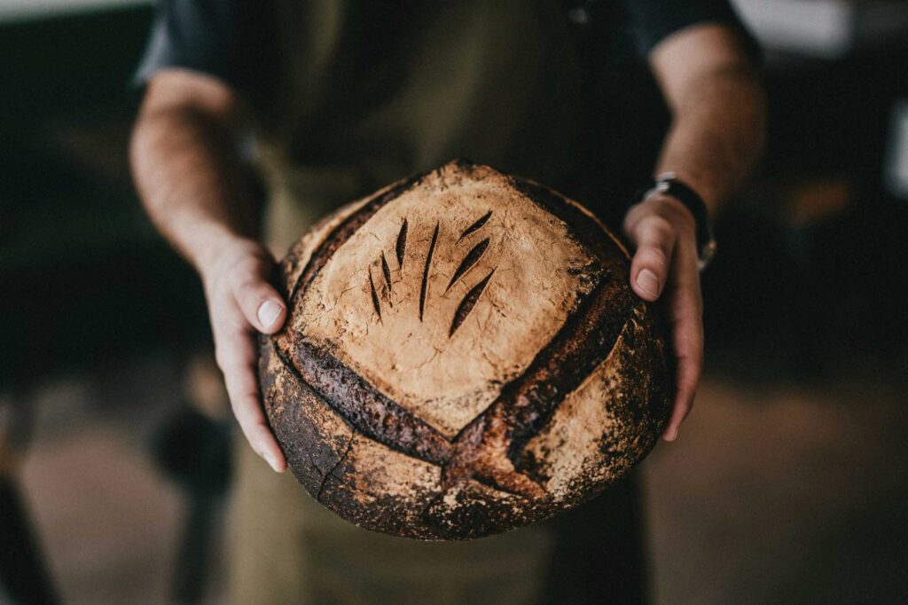 Frisch gebackenes, rustikales Brot in den Händen eines Bäckers aus Centro Italia, mit Tipps für die beste italienische Backerfahrung.