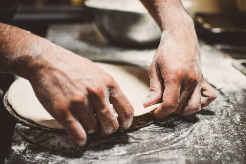 Italienischer Bäcker formt Teig auf einer bemehlten Arbeitsfläche in Centro Italia, mit Tipps für die beste italienische Kocherfahrung.