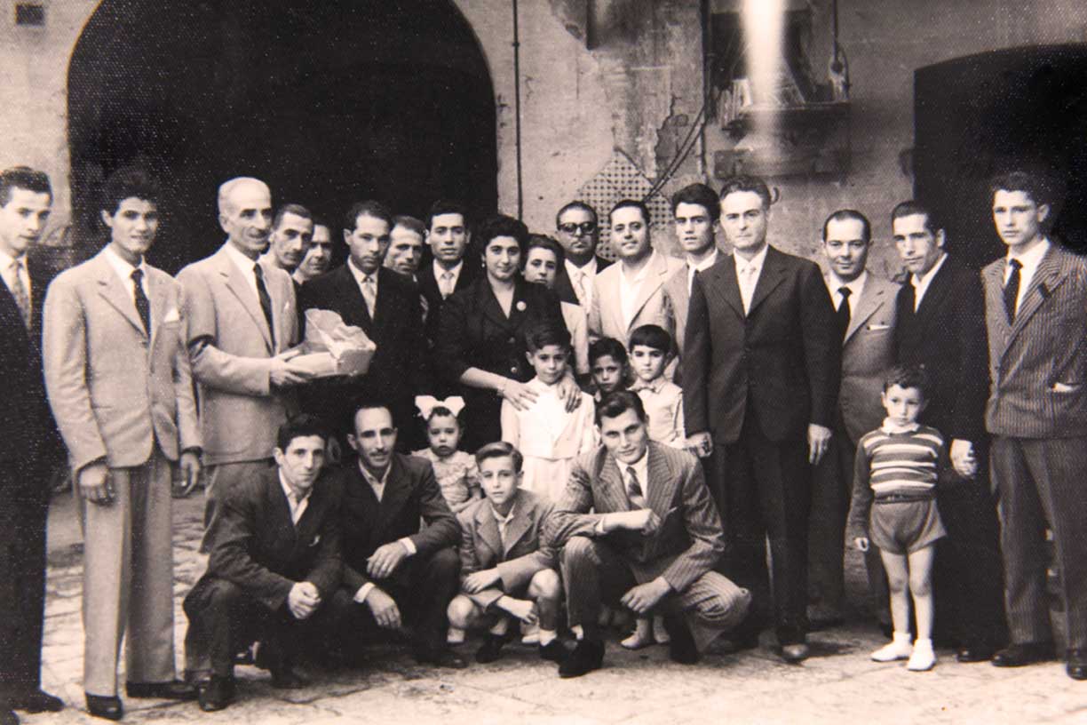 Historisches Schwarz-Weiß-Foto der Besitzerfamilie von Caputo. Die abgebildeten Männer, Frauen und Kinder posieren formell, das Bild scheint eine Feier oder ein bedeutendes Ereignis in der Geschichte des Mehlproduzenten Mulino Caputo festzuhalten