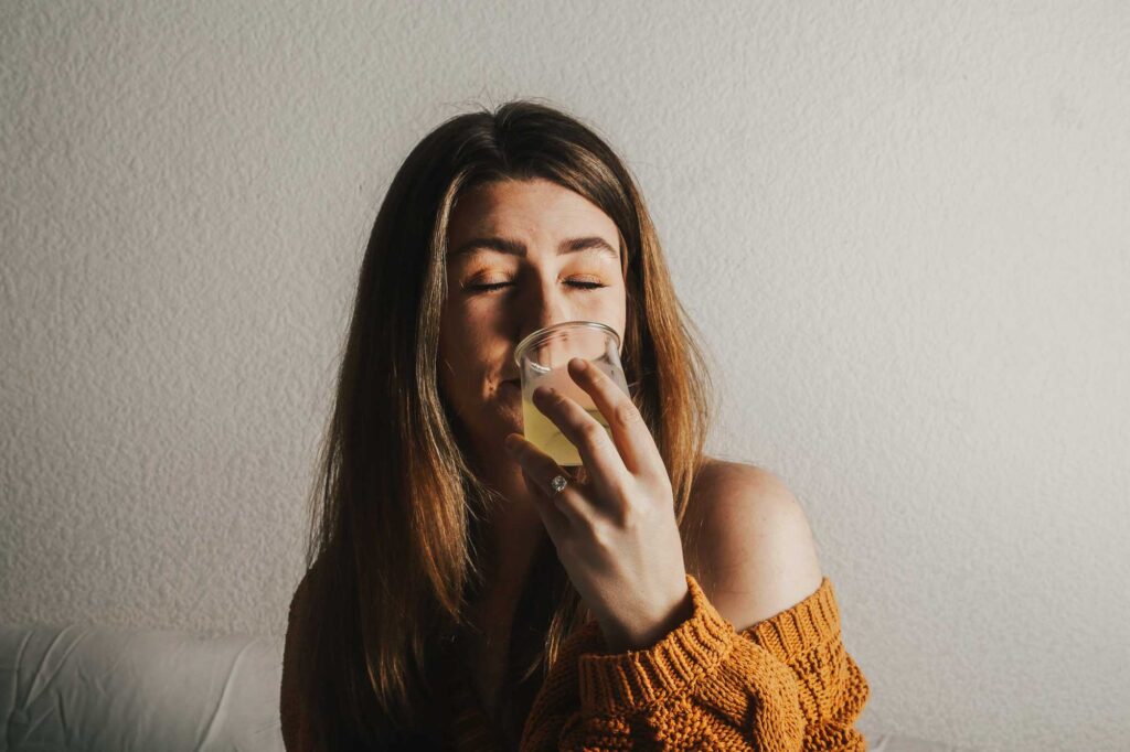 Eine Frau genießt ein Glas erfrischenden Limoncello. Sie hält das Glas nahe an ihre Nase und hat die Augen geschlossen, um das Aroma des italienischen Zitronenlikörs voll zu erfassen