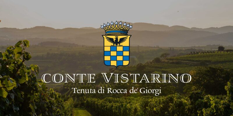 Weinberge des Weinguts Conte Vistarino in den sanften Hügeln von Rocca de’ Giorgi bei Sonnenuntergang, mit dem Logo des Weinguts im Vordergrund