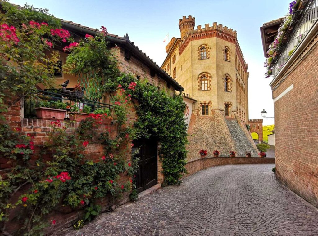 Das malerische Barolo-Schloss, umgeben von blühenden Gärten und charmanten Kopfsteinpflasterstraßen, ein Wahrzeichen der Region Piemont.