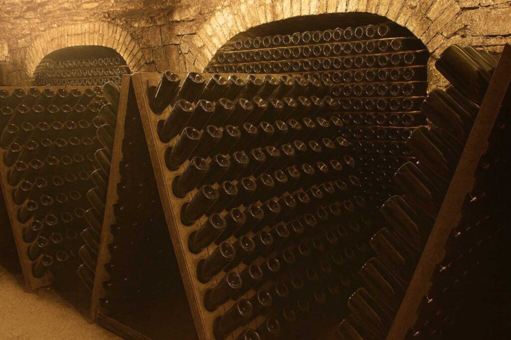 Traditioneller Weinkeller in Franciacorta mit hunderten Flaschen auf Rüttelpulten – klassische Flaschengärung nach Metodo Classico für edle Schaumweine.