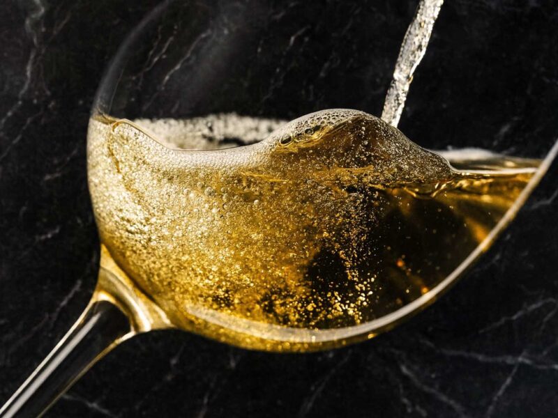 Goldener Franciacorta-Schaumwein wird ins Glas eingeschenkt – prickelnde Perlage und raffinierte Eleganz im Zeichen italienischer Exzellenz.