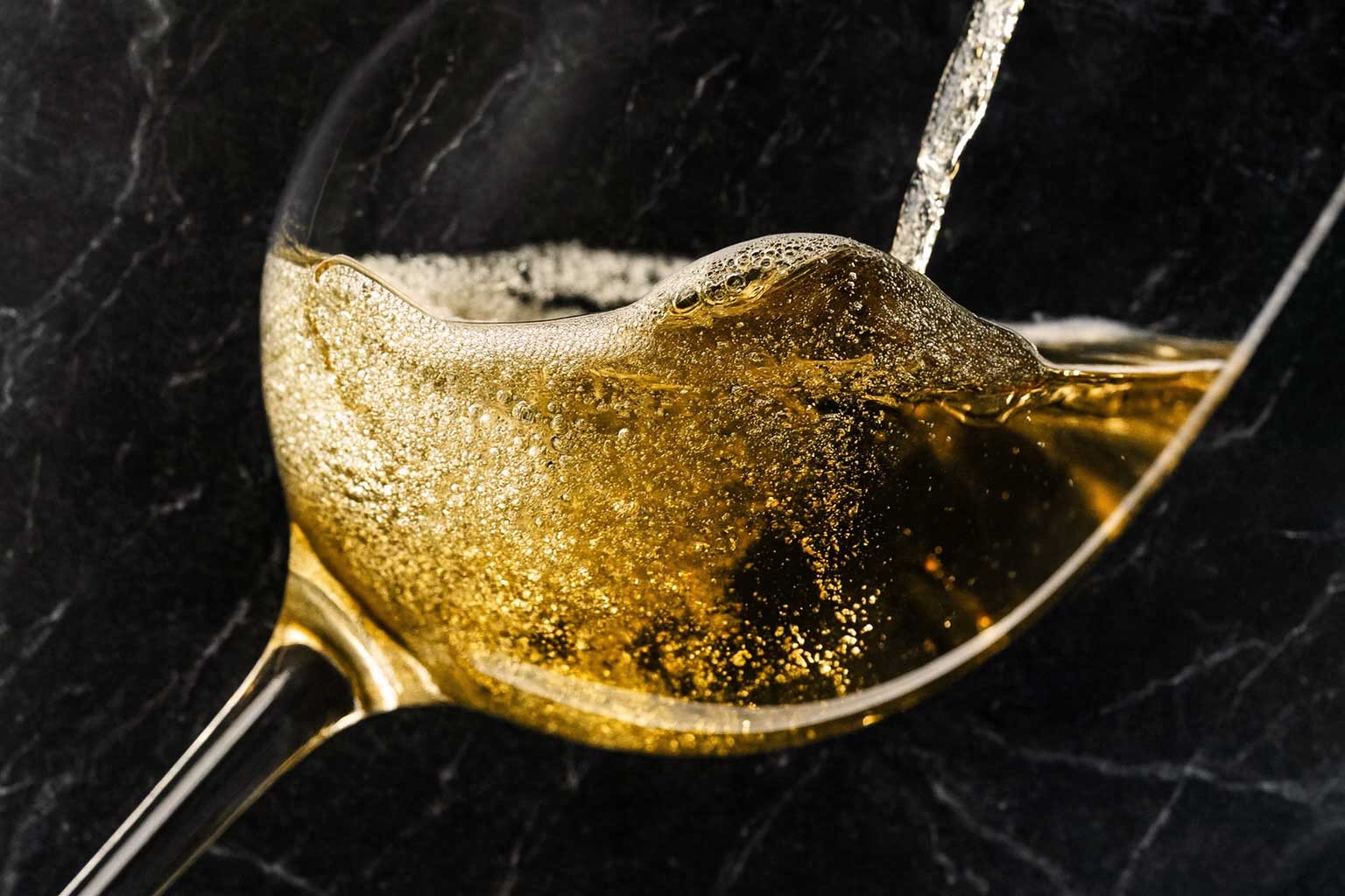Goldener Franciacorta-Schaumwein wird ins Glas eingeschenkt – prickelnde Perlage und raffinierte Eleganz im Zeichen italienischer Exzellenz.