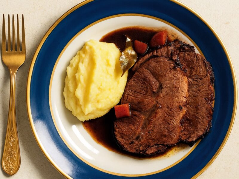 Zartes Brasato al Barolo mit cremigem Kartoffelpüree, angerichtet auf elegantem Porzellan, verfeinert mit Rotweinsauce – piemontesische Spezialität aus Rindfleisch und Barolo-Wein.