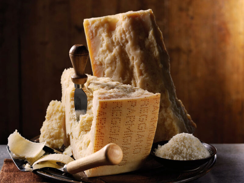 Parmigiano Reggiano Käse aufgeschnitten mit Käseschaufel und Reibkäse – italienischer Genuss pur.