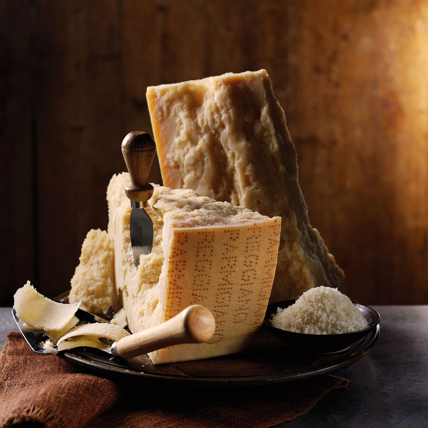 Parmigiano Reggiano Käse aufgeschnitten mit Käseschaufel und Reibkäse – italienischer Genuss pur.