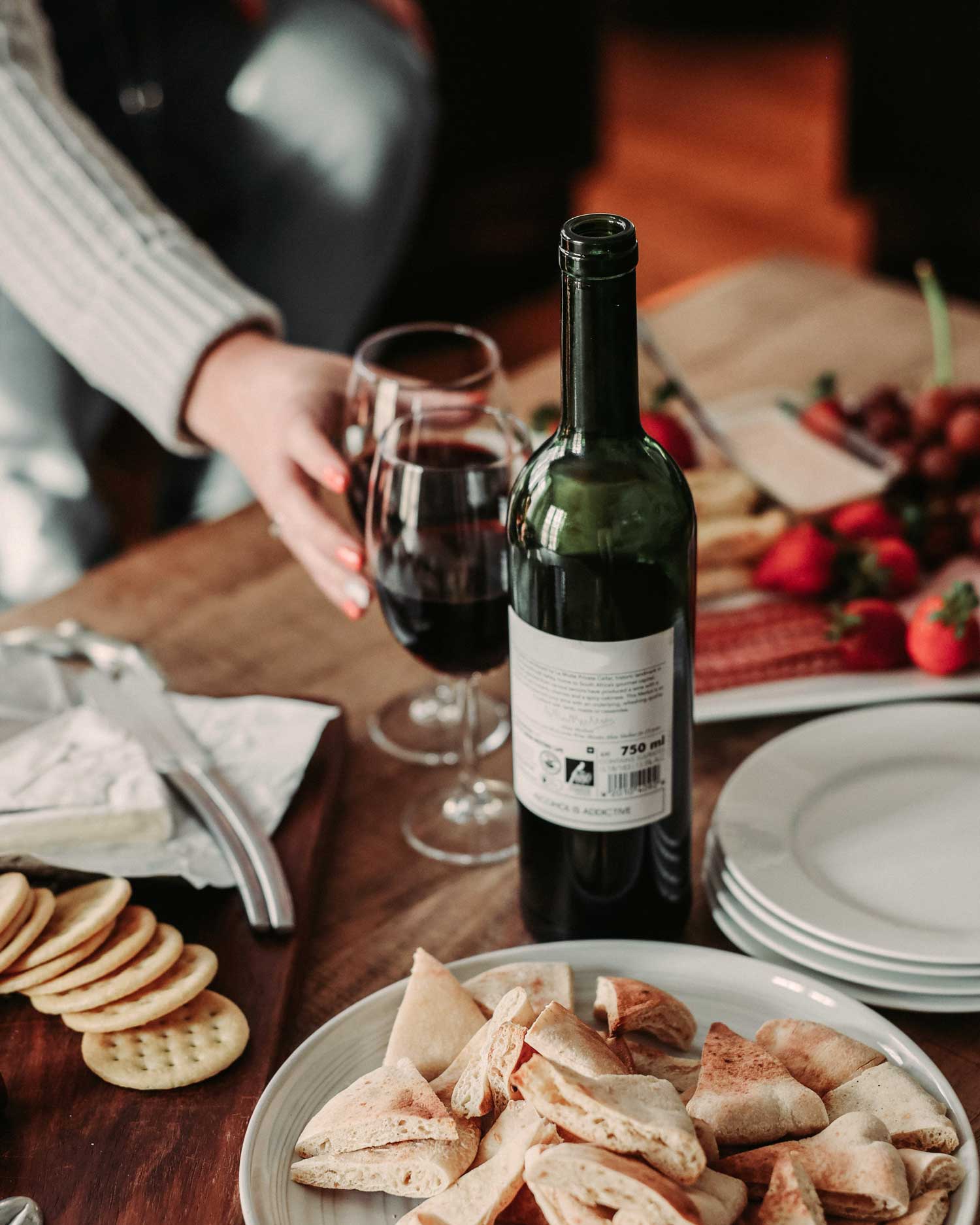 Ein gemütliches Abendessen mit Brot, Käse, frischen Früchten und einer Flasche Primitivo-Wein – der perfekte Moment für Genießer.