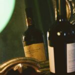 Stimmungsvolle Aufnahme einer Flasche Primitivo di Manduria, die sich in einem antiken Spiegel spiegelt. Der apulische Rotwein, bekannt für seine intensiven Aromen und kräftigen Noten, steht im Fokus eines neuen Artikels der Centro Italia Gazzetta über die Faszination und Geschichte des Primitivo-Weins.