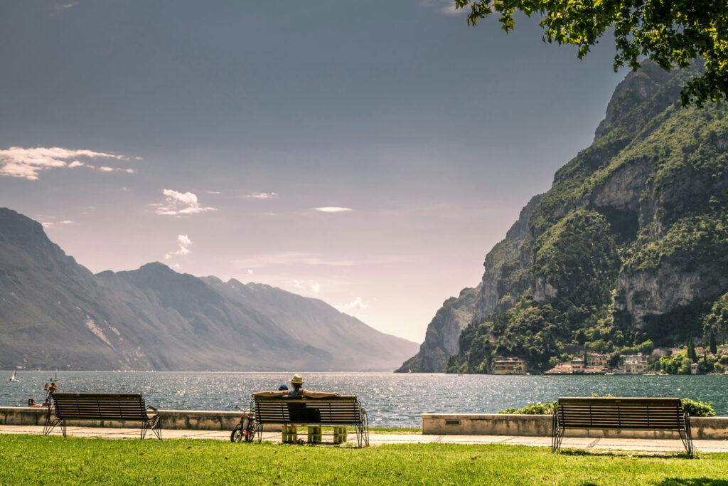 Malerischer Blick auf den Gardasee mit Bergen und Parkbänken im Vordergrund – idealer Ort, um ein Glas Lugana zu genießen.