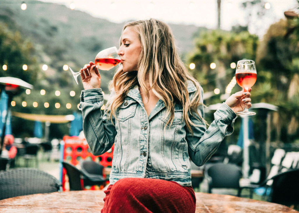 Frau genießt ein Glas Primitivo Roséwein im Freien, perfekte Darstellung der Leichtigkeit und Lebensfreude Apuliens.
