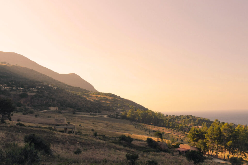 Hügelige Landschaft in Westsizilien bei Sonnenuntergang, mit Blick auf das Meer – Heimat des Marsalaweins.