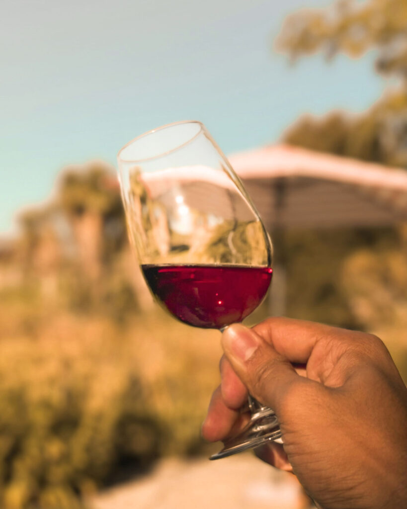 Hand hält ein Glas Marsalawein bei Sonnenlicht – warmer Farbton und Genussmoment.