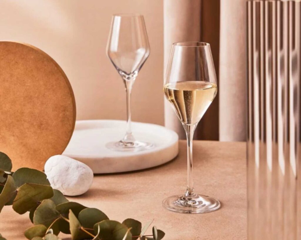 Ein stilvolles Glas Prosecco auf einem eleganten, minimalistisch dekorierten Tisch mit sanften Erdtönen – eine Einladung zu einem genussvollen Moment italienischer Lebensart.