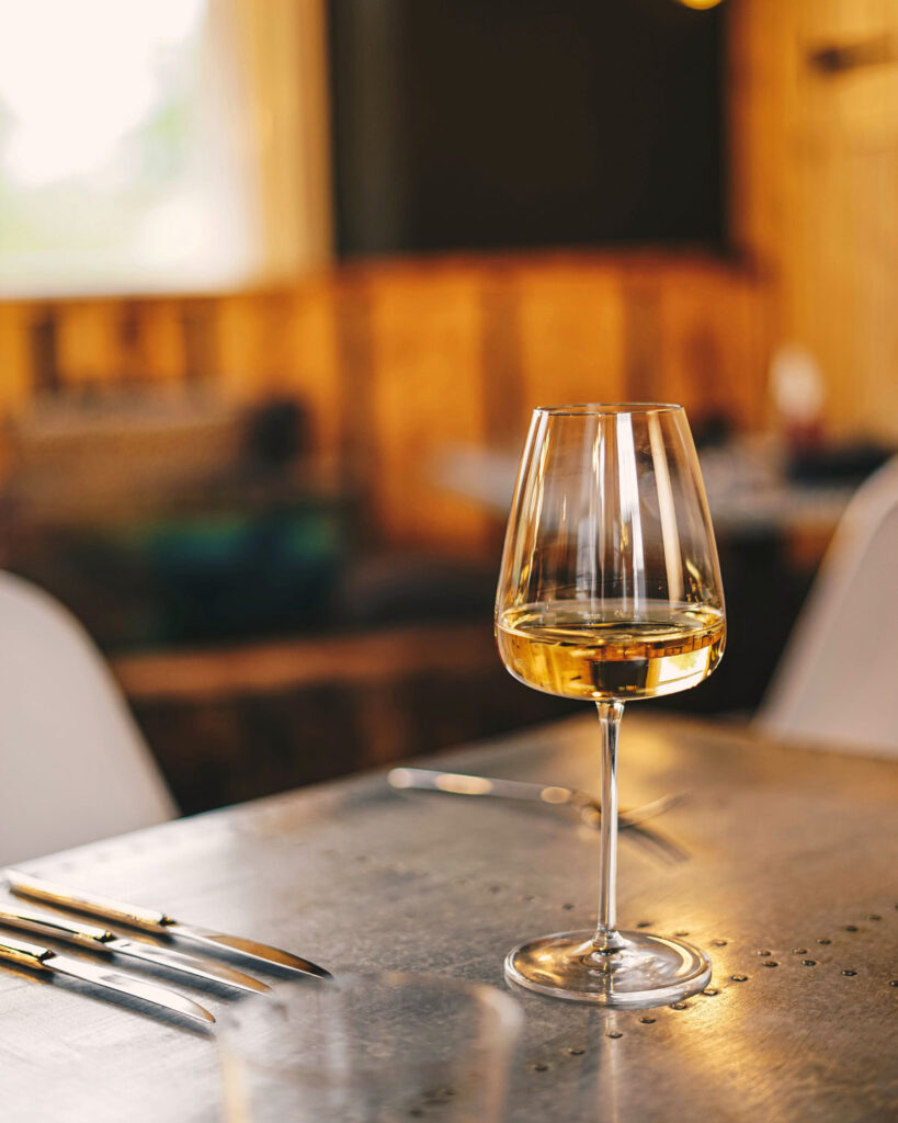 Ein elegantes Glas Riesling auf einem gedeckten Tisch in einem modernen Restaurant – Genussmoment im stilvollen Ambiente.