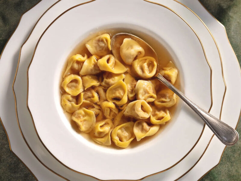 Traditionelle Tortellini in einer klaren Fleischbrühe, serviert in einem eleganten Suppenteller.