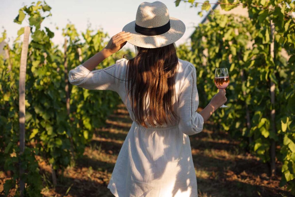 Frau mit Glas Bardolino Chiaretto im Weinberg – entspannter Genuss des typischen Roséweins vom Gardasee.
