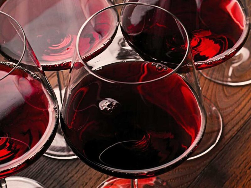 Mehrere Gläser mit rubinrotem Bardolino-Wein auf einem Holztisch – ein eleganter Einstieg in die Welt des italienischen Rotweins vom Gardasee.
