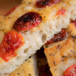 Detailaufnahme von frisch gebackener Focaccia Barese mit halbgetrockneten Tomaten und Oregano – goldbraun und fluffig.
