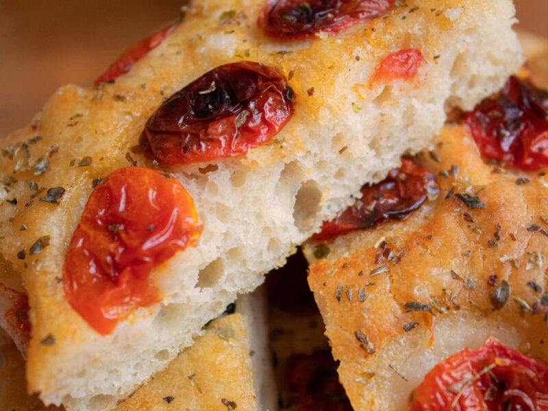 Detailaufnahme von frisch gebackener Focaccia Barese mit halbgetrockneten Tomaten und Oregano – goldbraun und fluffig.