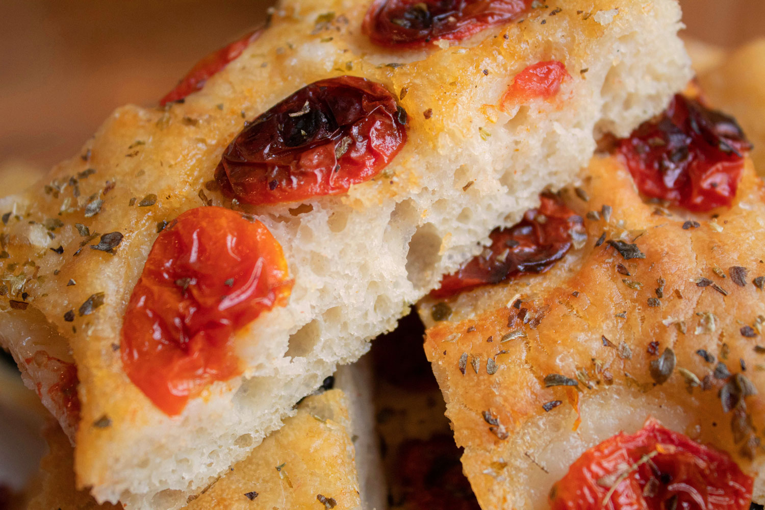 Detailaufnahme von frisch gebackener Focaccia Barese mit halbgetrockneten Tomaten und Oregano – goldbraun und fluffig.