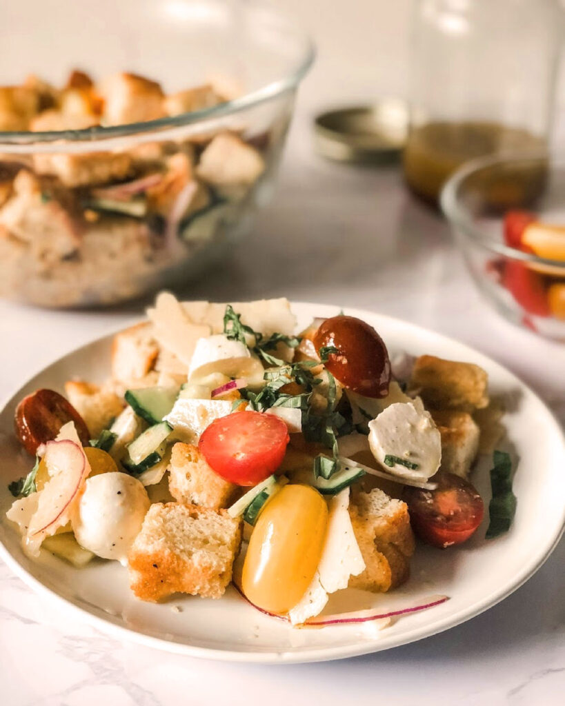 Italienischer Brotsalat (Panzanella) mit Tomaten, Mozzarella, Gurke, Basilikum und Focaccia-Würfeln.