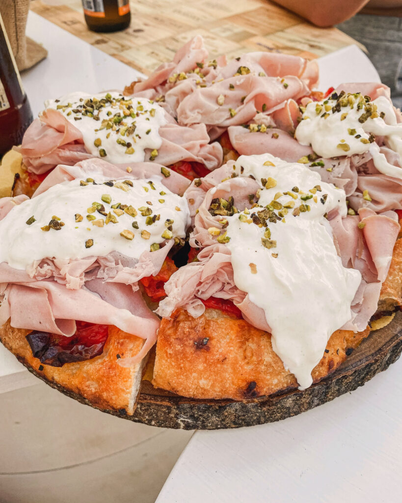 Gourmet-Focaccia mit Mortadella, Stracciatella und gehackten Pistazien belegt.