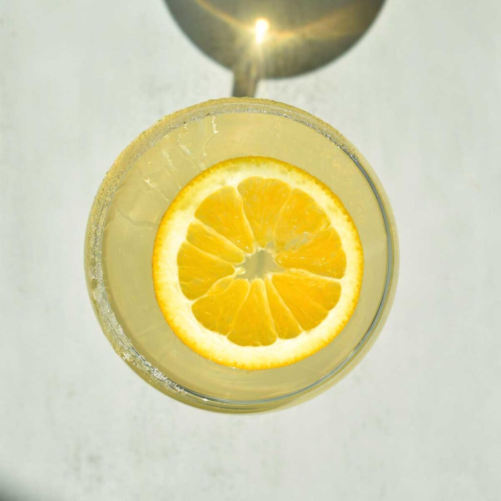 Nahaufnahme eines Limoncello Spritz mit einer großen Zitronenscheibe von oben gesehen, perfekt für sonnige Aperitivo-Momente.