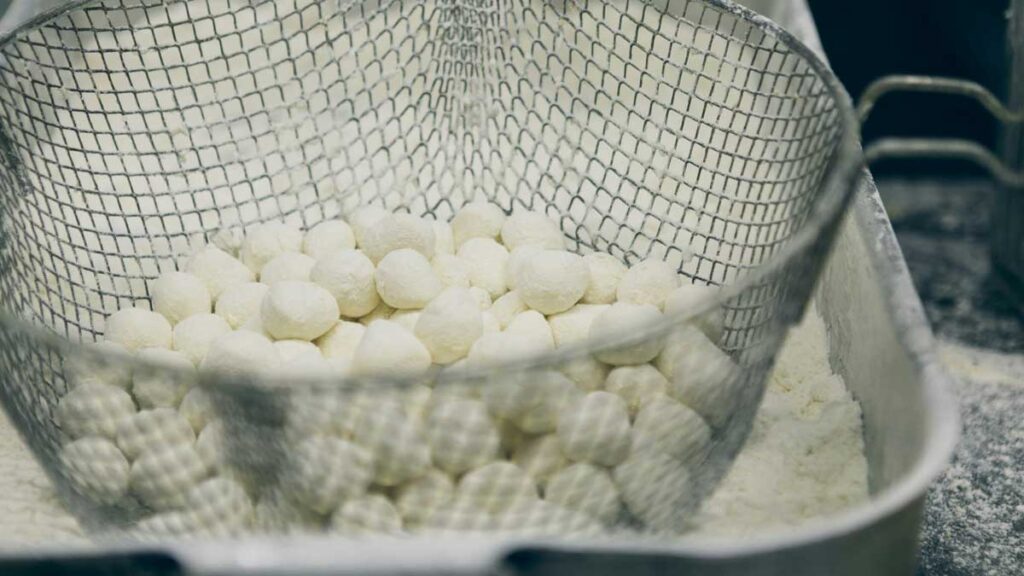 Frisch geformte Mini-Mozzarella-Kugeln in einem Abtropfsieb – bereit zum Verpacken.
