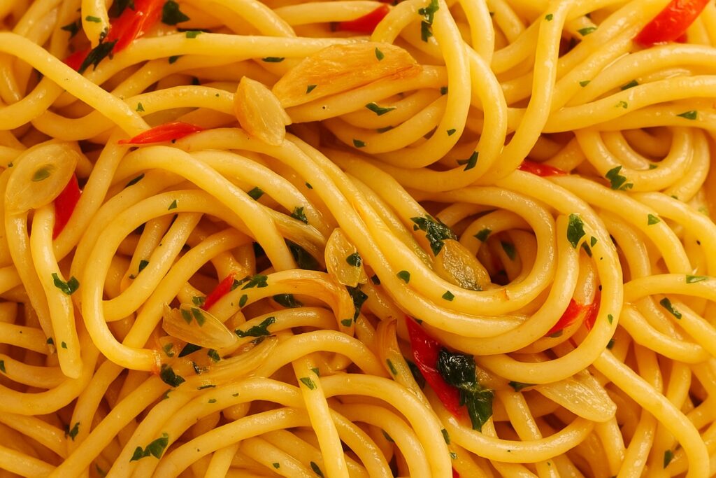 Makroaufnahme von Spaghetti Aglio, Olio e Peperoncino mit geröstetem Knoblauch, Petersilie und scharfen Peperoncini-Streifen – perfekt glänzende Textur.