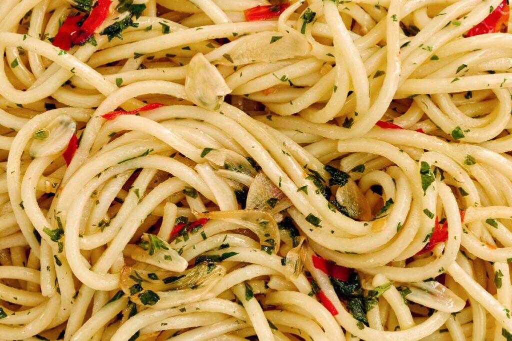 Makroaufnahme von Spaghetti Aglio, Olio e Peperoncino mit gebratenem Knoblauch, Chili und Petersilie – klassische italienische Einfachheit.