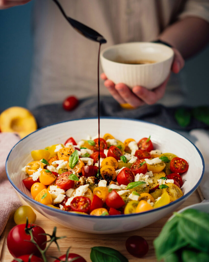 Caprese-Salat modern interpretiert: bunte Cherrytomaten, Mozzarella und Basilikum mit einem Schuss Balsamico, lebendig und frisch.