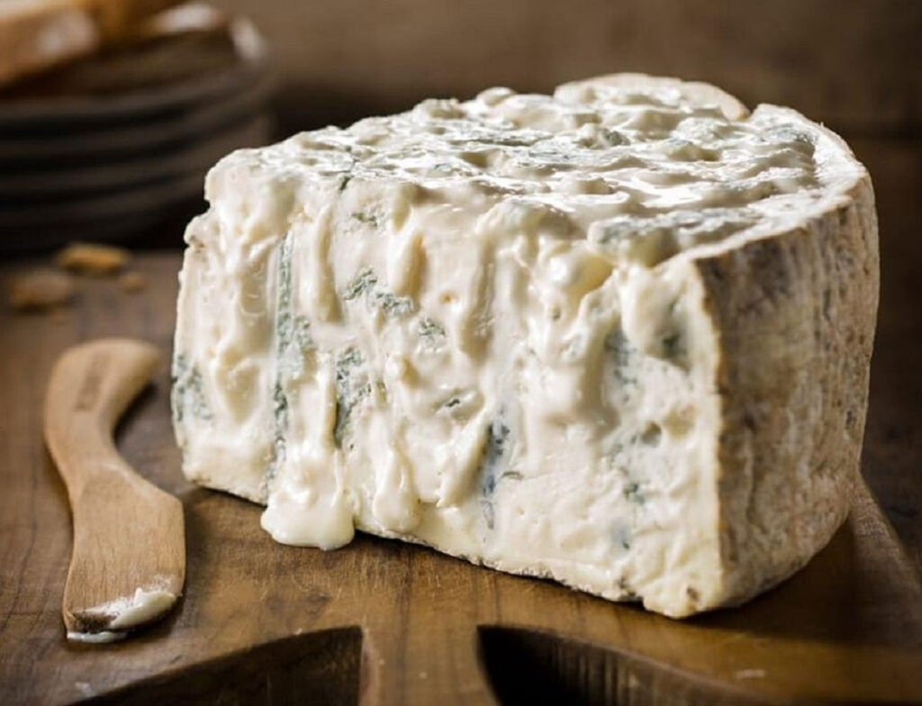 Cremiger Gorgonzola mit typischen Edelschimmeladern auf einem Holzbrett serviert – ein Klassiker der italienischen Käsekunst.