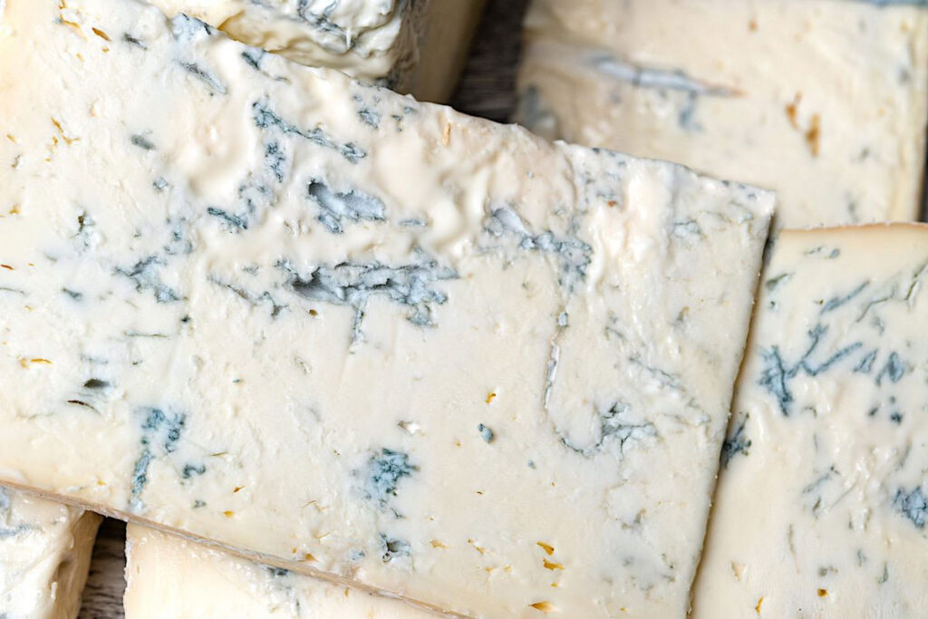 Nahaufnahme von cremigem Gorgonzola mit deutlich sichtbaren blauen Edelschimmel-Marmorierungen.