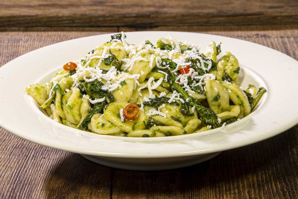 Traditionelles Gericht Orecchiette alle cime di rapa, garniert mit geriebenem Ricotta salata und Peperoncino.