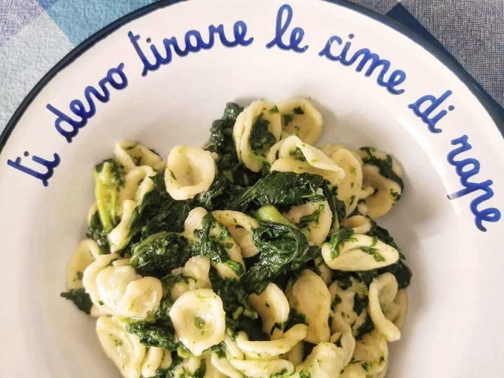 Teller mit Orecchiette alle cime di rapa, serviert auf einem dekorativen Teller mit dem Schriftzug „ti devo tirare le cime di rapa“.