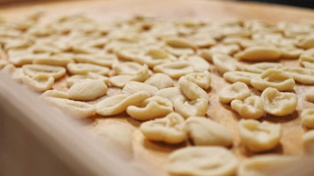 Frisch geformte Orecchiette auf einem Holzbrett zum Trocknen ausgebreitet.