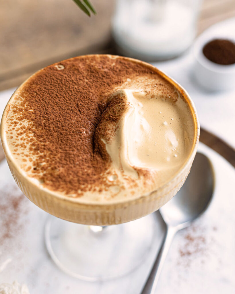Cremiger Spumone al Caffè in einem eleganten Coupe-Glas, mit einer großzügigen Schicht Kakaopulver bedeckt – eine sommerliche italienische Kaffeeverführung.