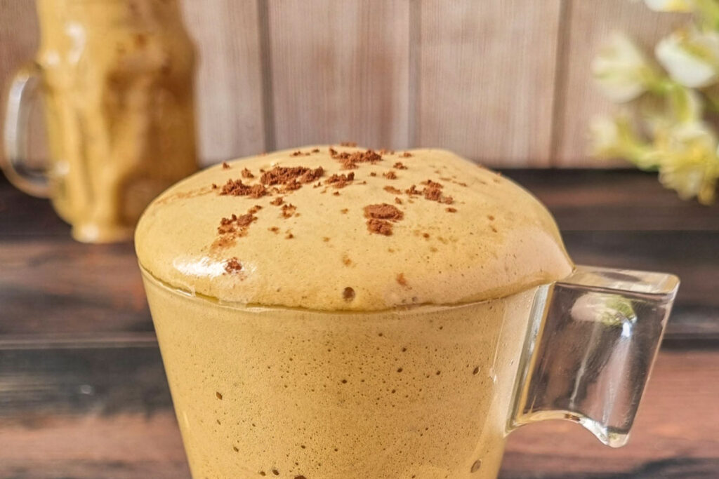 Cremiger Kaffee-Spumone mit dichter Schaumkrone in einer Glastasse, verziert mit Kakaosplittern – ein hausgemachter Desserttraum.