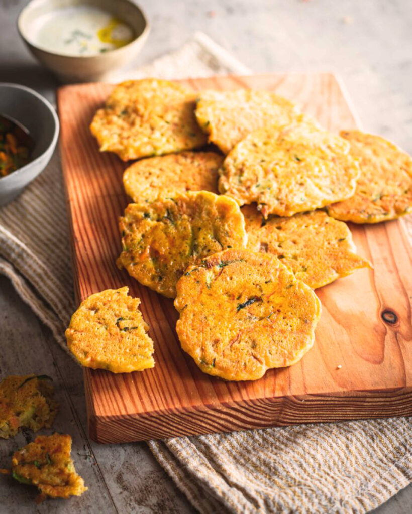 Knusprige Kichererbsen-Frittelle frisch gebraten auf einem Holzbrett serviert, begleitet von Dip-Saucen – ein typisches Gericht aus der italienischen Hausmannskost.