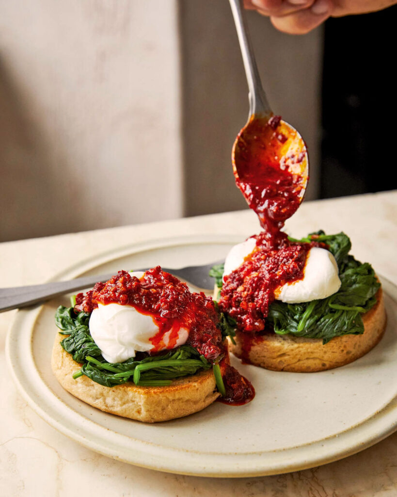 Zwei pochierte Eier auf sautiertem Blattspinat und geröstetem Brot, großzügig mit würziger kalabrischer ’Nduja bestrichen – ein moderner Brunch-Klassiker mit mediterraner Schärfe.