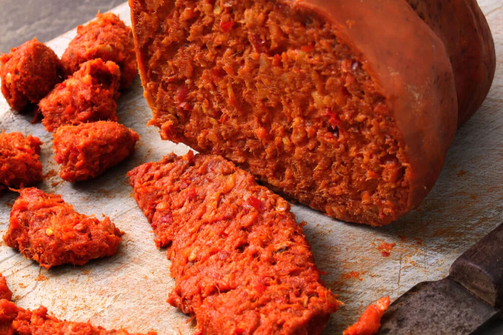 Detailaufnahme einer aufgeschnittenen ’Nduja-Wurst mit grober, streichfähiger Textur und scharfer Paprika – typisch kalabrische Delikatesse.