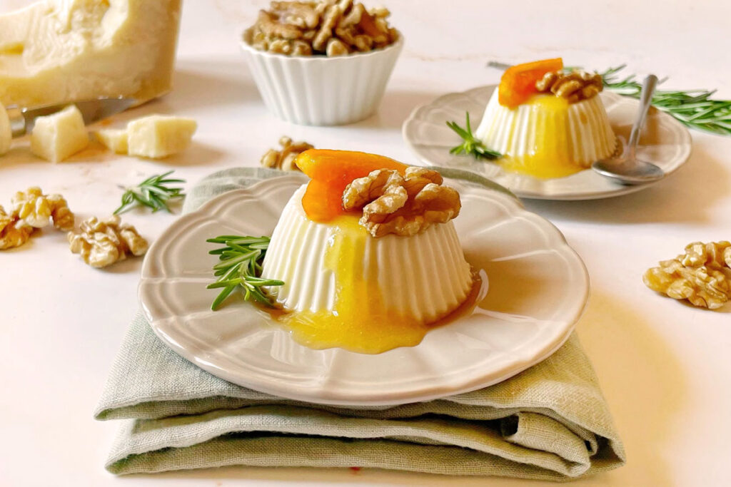 Herzhafte Panna Cotta mit Parmesan, Walnüssen, Aprikosensauce und Rosmarin, serviert auf einem cremefarbenen Teller.