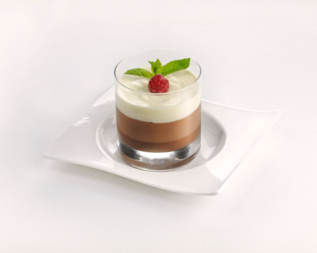 Schichtdessert aus Schokoladenmousse und Panna Cotta im Glas, verziert mit Himbeere und Minze – ein italienisches Highlight.